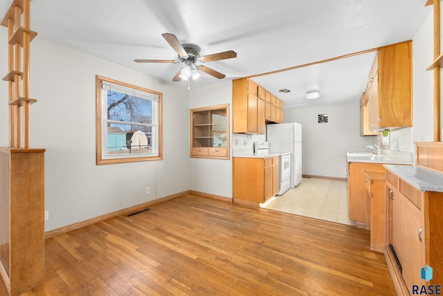 kitchen featuring light wood-style flooring, a sink, visible vents, light countertops, and white range with electric stovetop