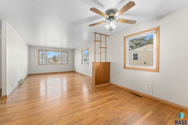 unfurnished room with light wood-type flooring, visible vents, and baseboards