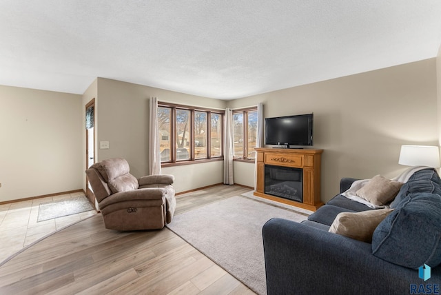 living area with a textured ceiling, light wood-style flooring, and baseboards