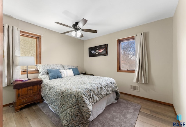 bedroom featuring light wood-style flooring, visible vents, ceiling fan, and baseboards