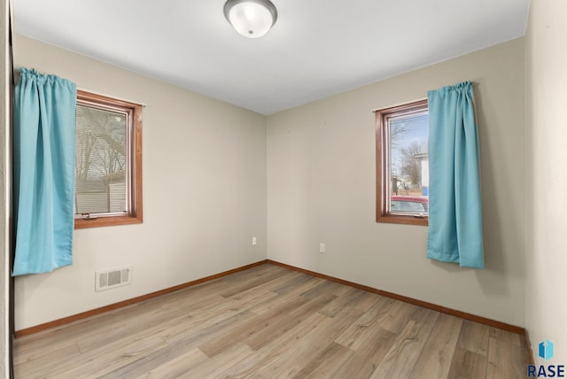 spare room with baseboards, visible vents, and light wood-style floors