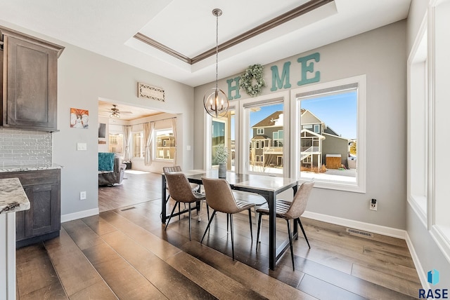 dining room featuring visible vents, a tray ceiling, dark wood finished floors, and baseboards