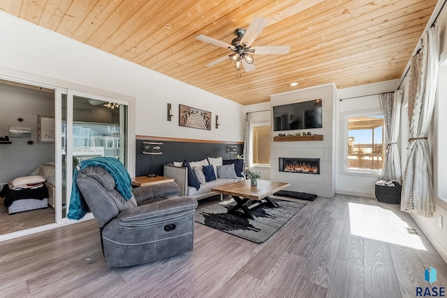 living area featuring lofted ceiling, wooden ceiling, a fireplace, and wood finished floors