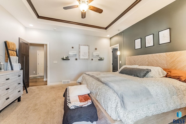 bedroom with a raised ceiling, light colored carpet, visible vents, ornamental molding, and baseboards