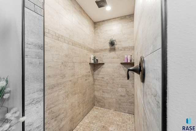 bathroom with tiled shower and visible vents