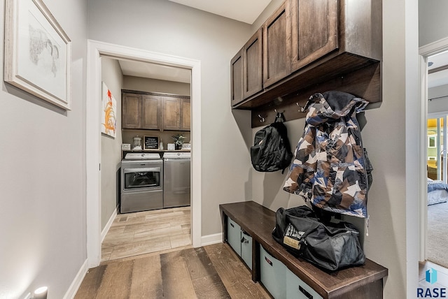 mudroom with wood finished floors, washing machine and clothes dryer, and baseboards