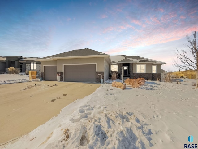 prairie-style home with a garage, stone siding, and stucco siding