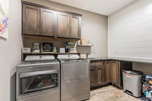 washroom featuring cabinet space, washing machine and dryer, and a sink