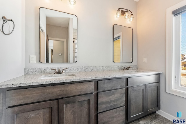 full bathroom with a sink, baseboards, and double vanity