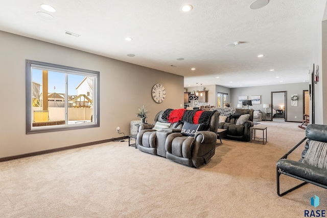 living area with a healthy amount of sunlight, baseboards, a textured ceiling, and light colored carpet