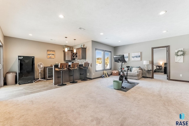 exercise area featuring a dry bar, recessed lighting, visible vents, light carpet, and a textured ceiling