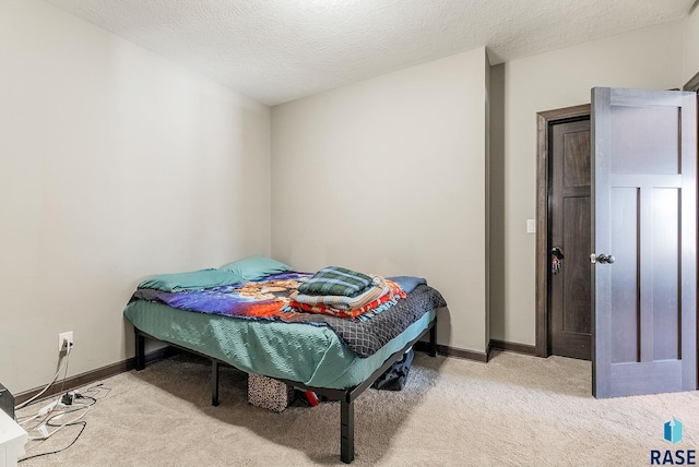 bedroom featuring light colored carpet, a textured ceiling, and baseboards