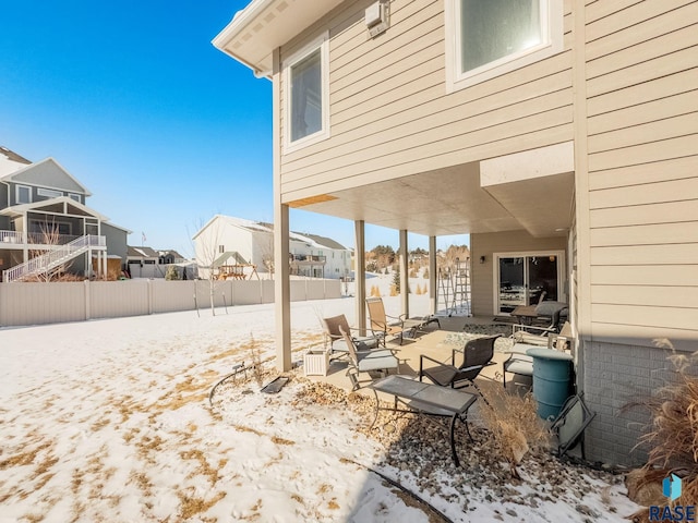 snow covered patio with a residential view and fence