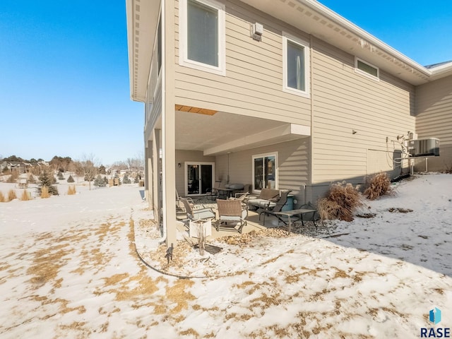 snow covered back of property with a patio area and central AC unit