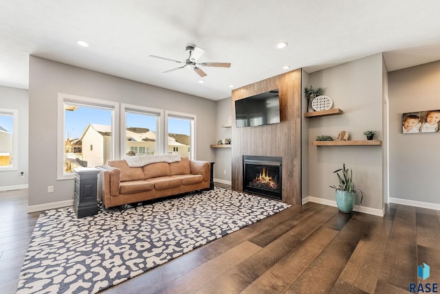 living room with baseboards, dark wood finished floors, ceiling fan, a fireplace, and recessed lighting