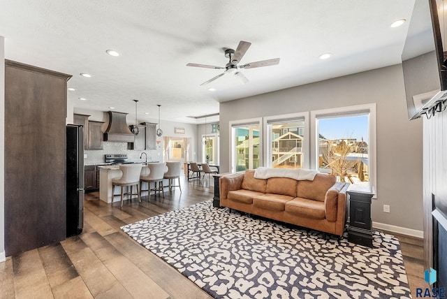 living area with ceiling fan, dark wood-type flooring, recessed lighting, and baseboards