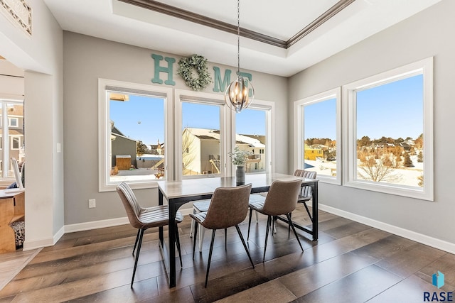 dining room with dark wood-type flooring, a raised ceiling, ornamental molding, and baseboards