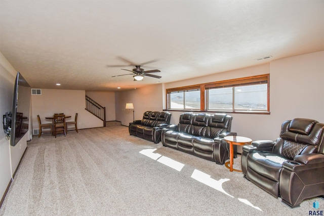 living area featuring light carpet, ceiling fan, stairway, and visible vents