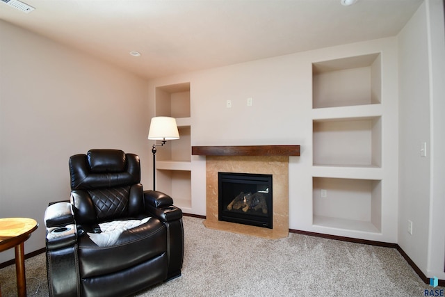 carpeted living room featuring built in shelves, a tile fireplace, visible vents, and baseboards