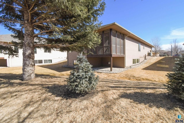 view of home's exterior with a sunroom and a lawn