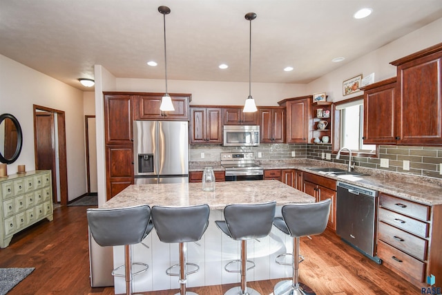 kitchen featuring pendant lighting, a center island, stainless steel appliances, open shelves, and a sink