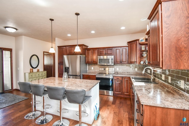 kitchen featuring a center island, decorative light fixtures, open shelves, stainless steel appliances, and a sink