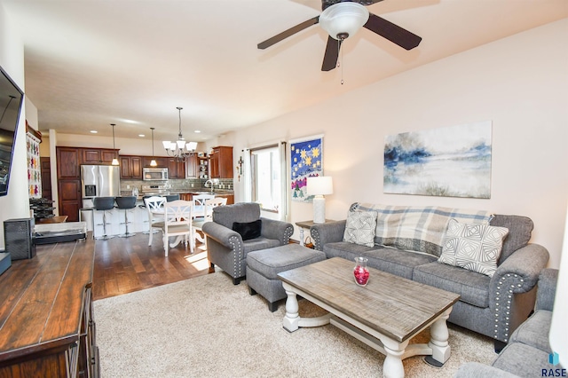 living area featuring light wood-style floors and ceiling fan with notable chandelier