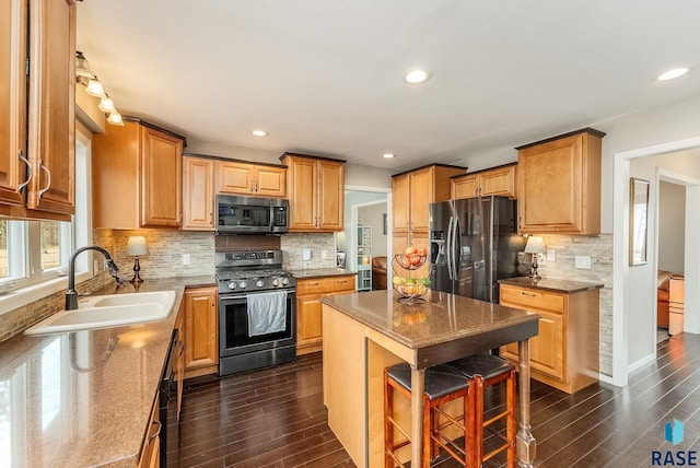 kitchen with decorative backsplash, brown cabinetry, dark wood-style floors, stainless steel appliances, and a sink