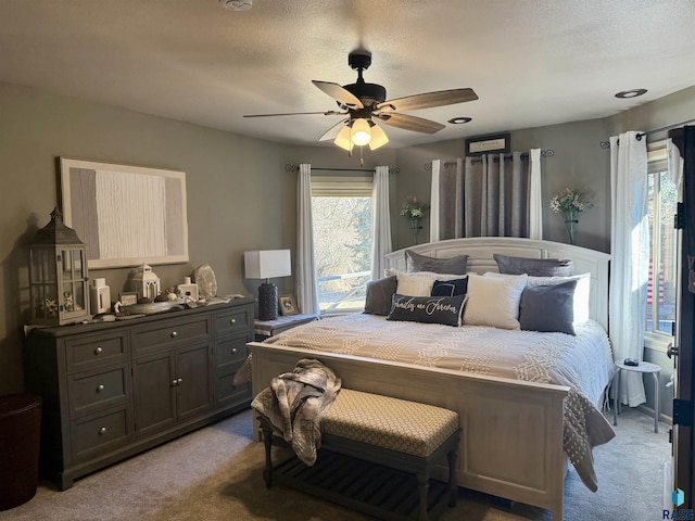 bedroom featuring ceiling fan, a textured ceiling, and light colored carpet