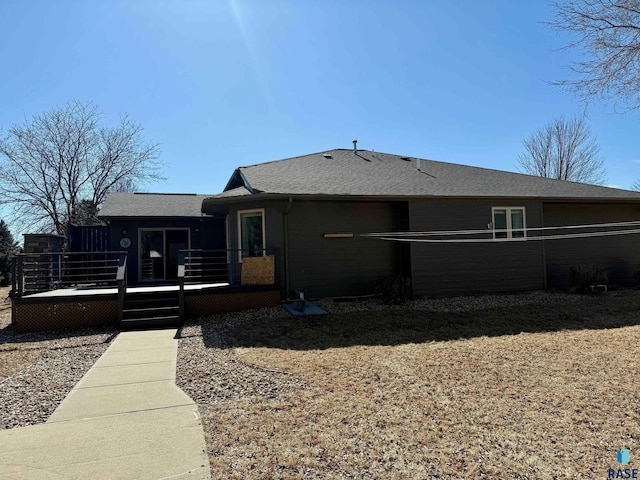 rear view of property with a shingled roof and a wooden deck