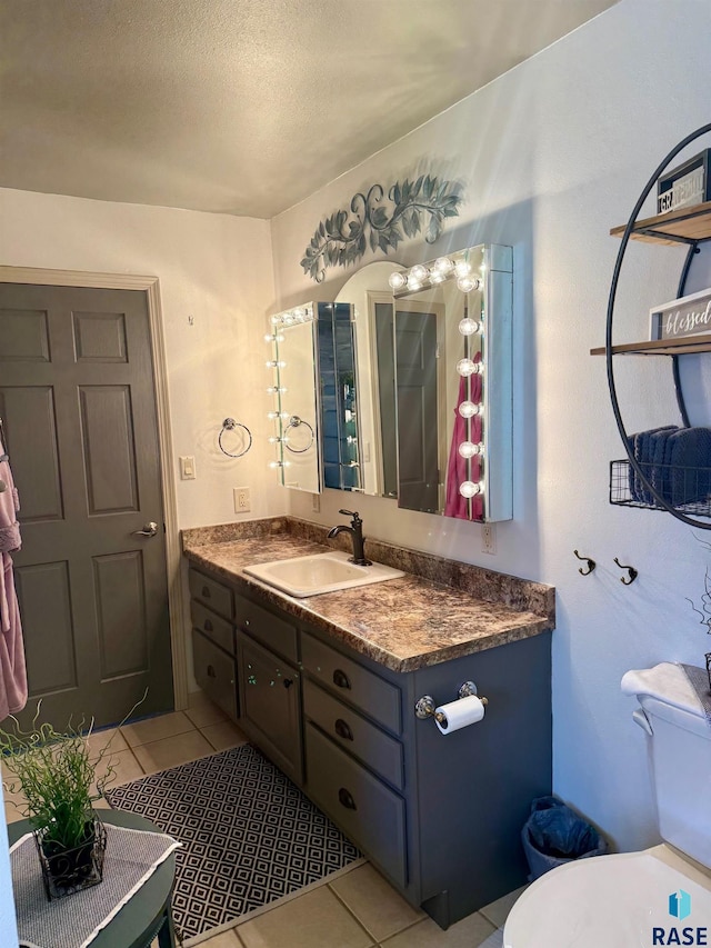 bathroom featuring toilet, vanity, a textured ceiling, and tile patterned floors