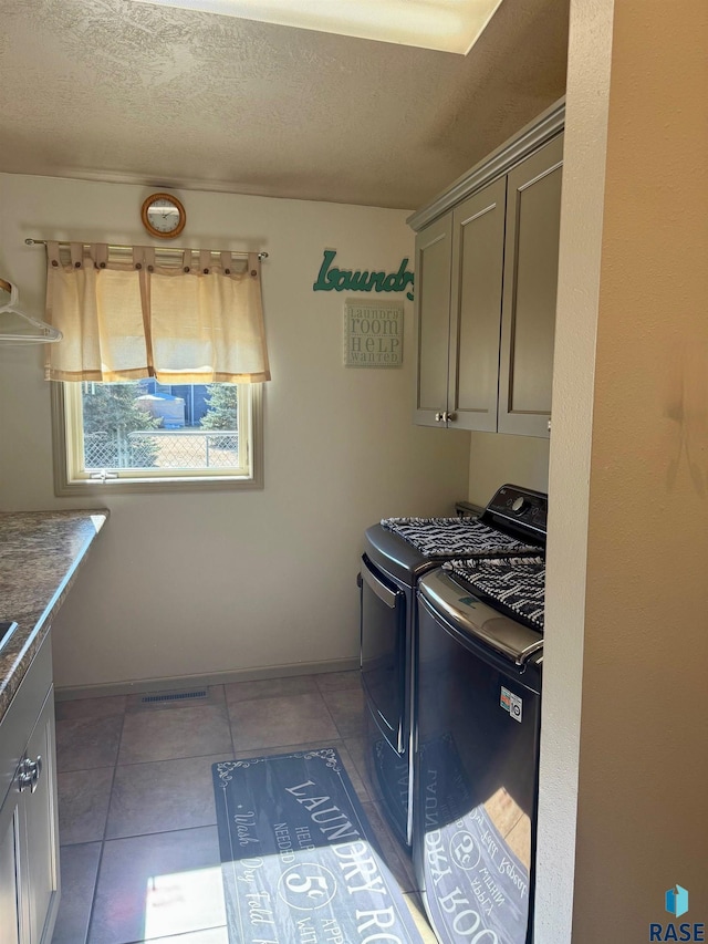 laundry room with cabinet space, independent washer and dryer, a textured ceiling, and light tile patterned flooring