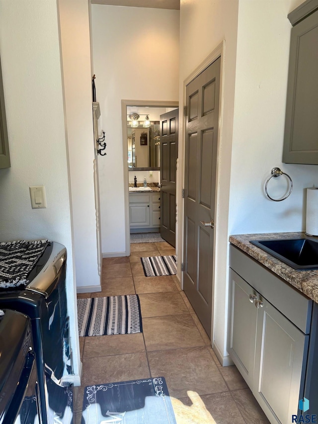 kitchen with gray cabinets, a sink, baseboards, and light tile patterned floors