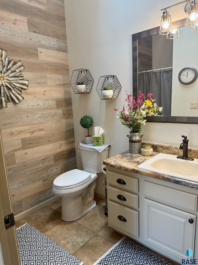 bathroom featuring wooden walls, vanity, toilet, and tile patterned floors