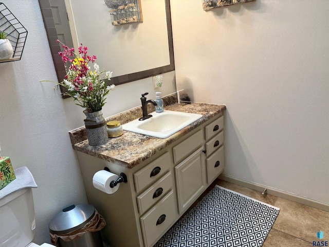 bathroom featuring baseboards, vanity, toilet, and tile patterned floors