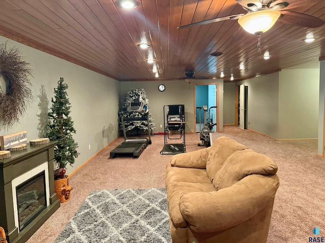 living room featuring carpet flooring, a glass covered fireplace, and wood ceiling