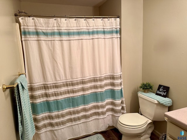 bathroom with toilet, a shower with shower curtain, vanity, and baseboards