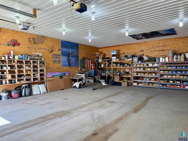 garage featuring metal wall, a workshop area, and a garage door opener