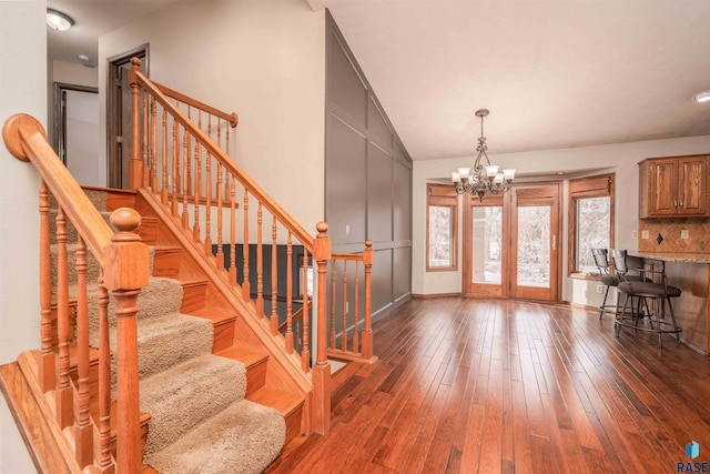 entrance foyer featuring stairway, baseboards, a chandelier, and dark wood-type flooring