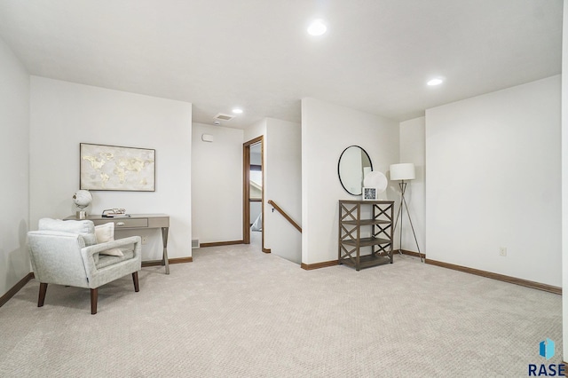 sitting room featuring light carpet, baseboards, and an upstairs landing