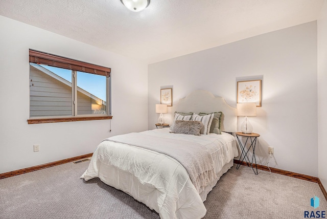 bedroom with carpet flooring, visible vents, baseboards, and a textured ceiling