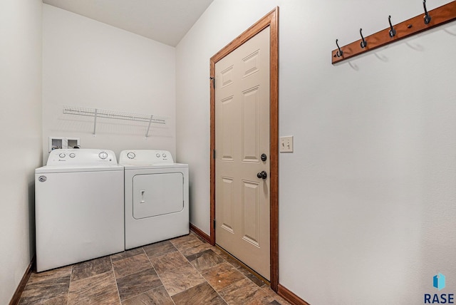 clothes washing area with baseboards, laundry area, stone finish flooring, and washer and dryer