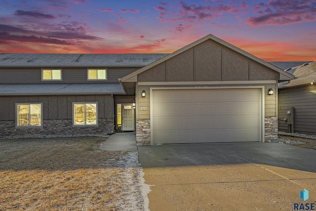 view of front facade with a garage, stone siding, and driveway