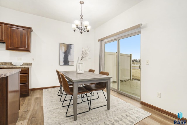 dining room with a chandelier, light wood-style flooring, and baseboards