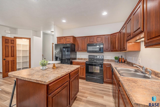 kitchen featuring light countertops, a kitchen island, a sink, light wood-type flooring, and black appliances