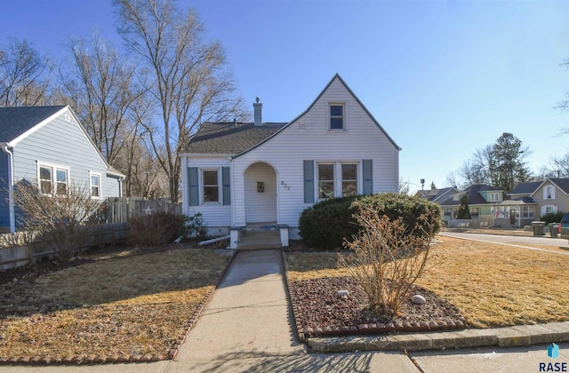 view of front of home with a chimney and fence