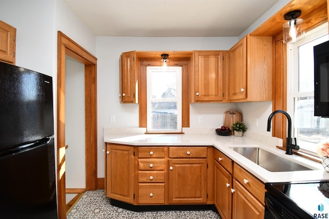 kitchen featuring brown cabinets, light countertops, a sink, and freestanding refrigerator