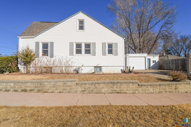 view of home's exterior with an outbuilding, a garage, fence, concrete driveway, and roof with shingles