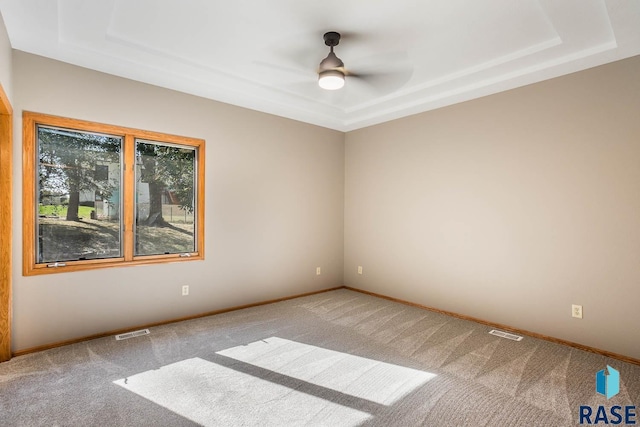 carpeted empty room featuring baseboards, visible vents, and a ceiling fan