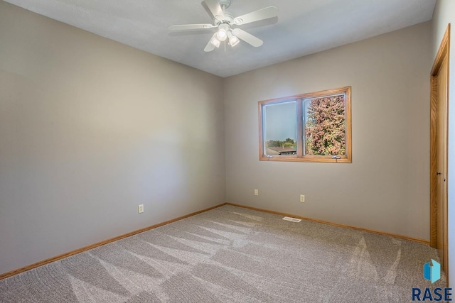 carpeted empty room with a ceiling fan, visible vents, and baseboards